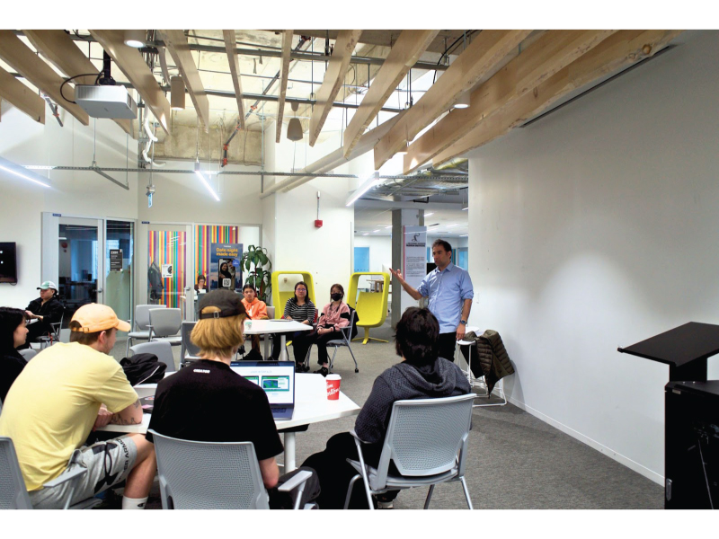 Hossein Rahnama teaching his creative ai class in a room to his students