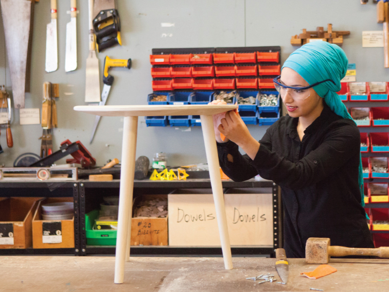 A woman builds a table out of wood in a workshop