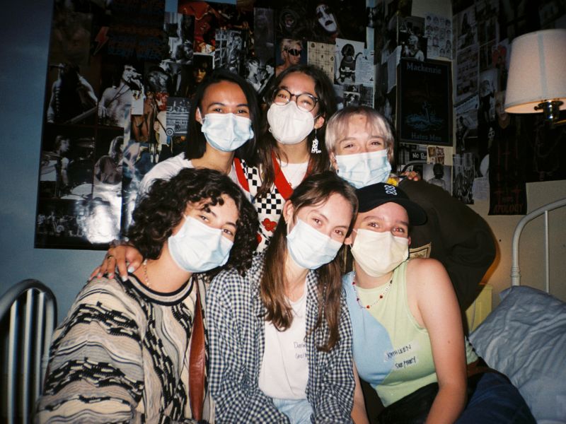 A flash photo of a group of filmmakers cheerfully behind masks on a film set.