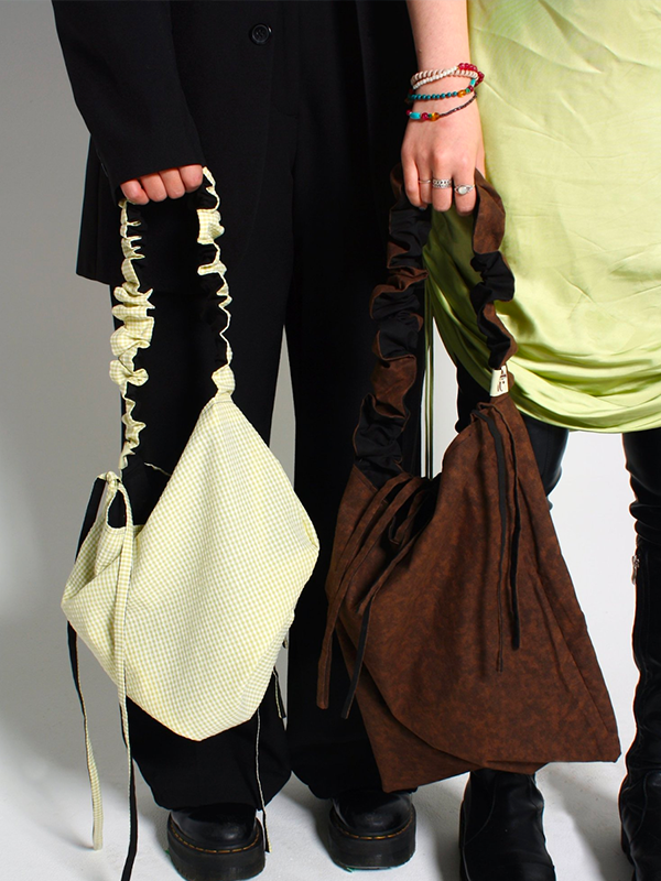 Two models are standing next to each other, holding bags in their hands from the brand Spicy Princess.