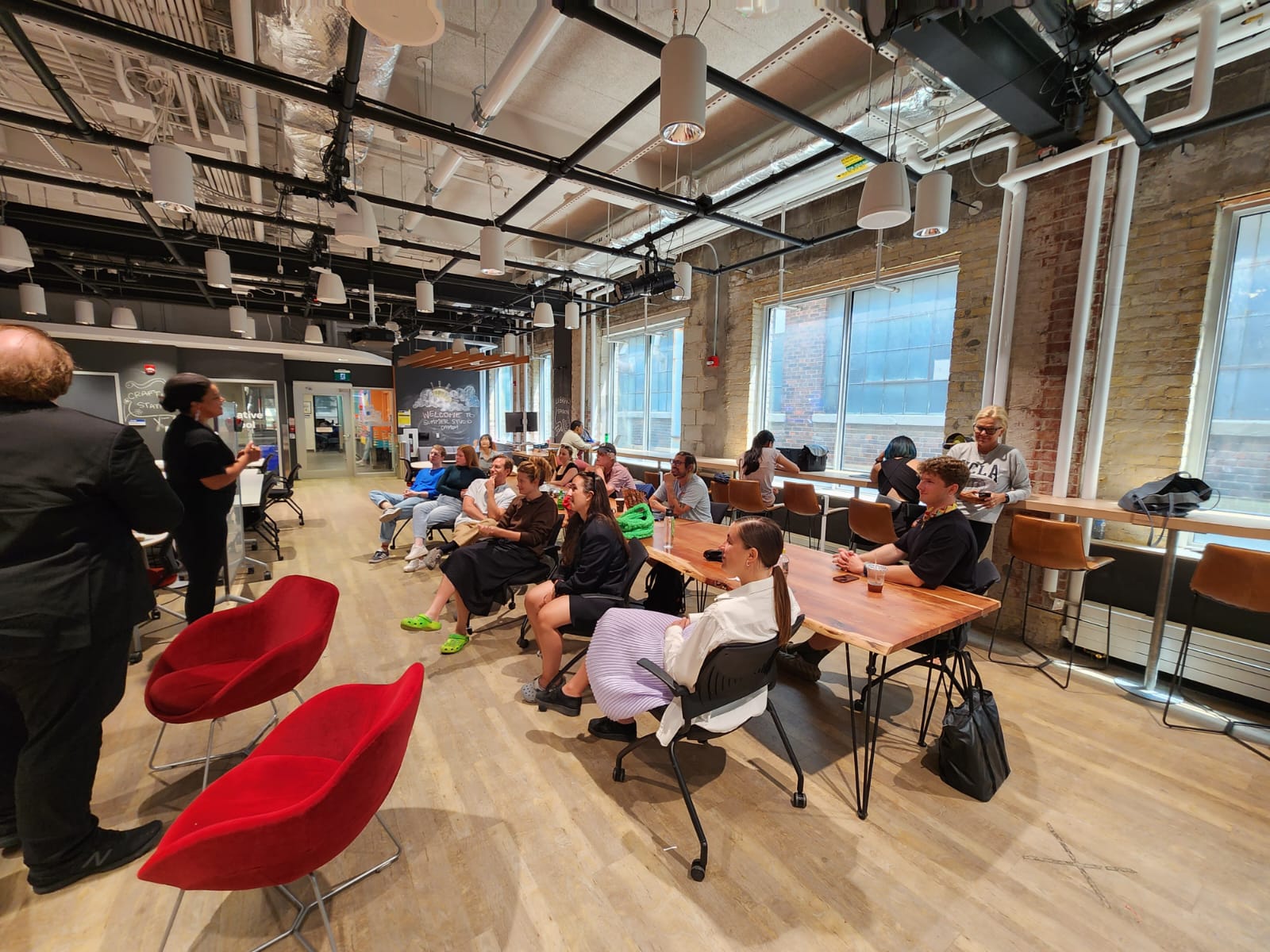 Students listening to the instructor lecture in an open space classroom.