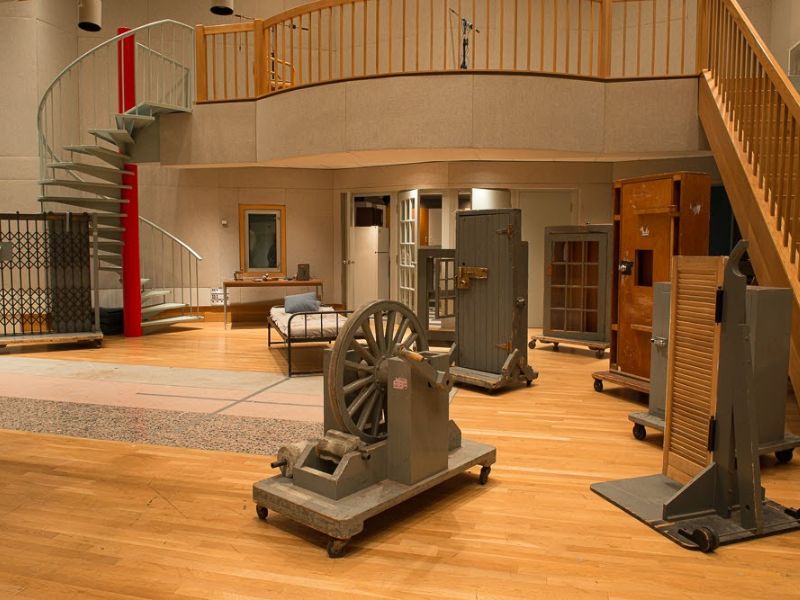 A large room housing various props and two staircases leading to a loft