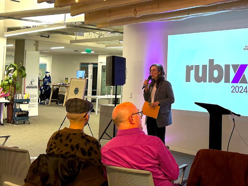 Associate Dean Dr. Natalie Alvarez stands and delivers a speech into a microphone in front of the seated audience.