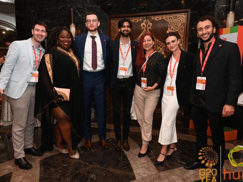 A group of young adults in business attire smile brightly for a photograph