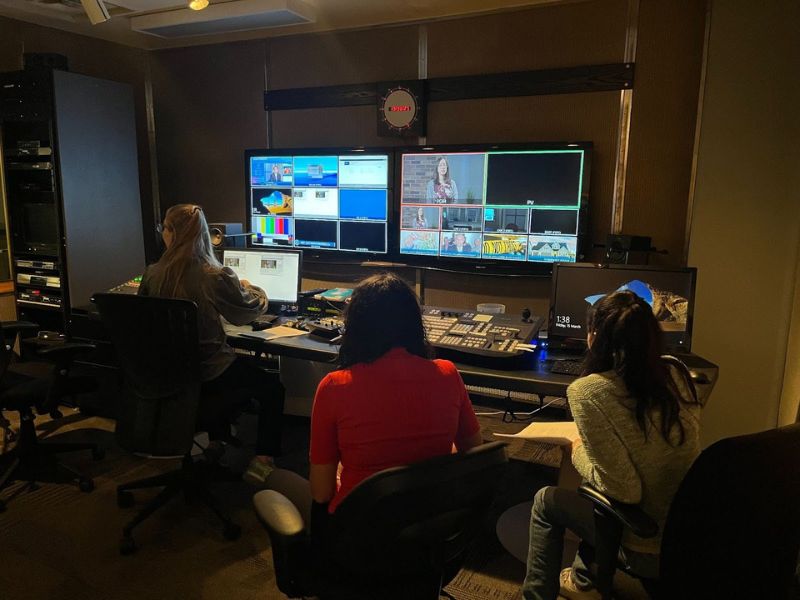 3 people in the broadcasting room reviewing and editing interview footage 