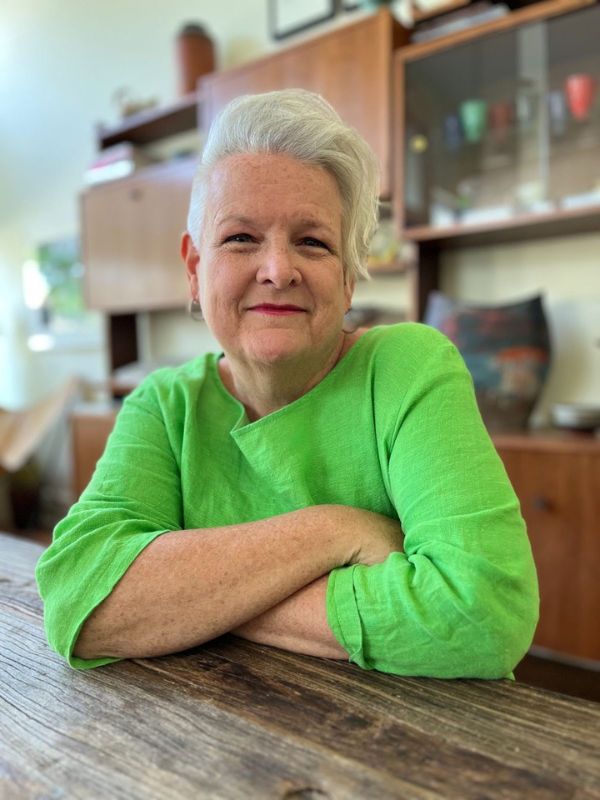 A woman wearing a bright green shirt smiles warmly at the camera.