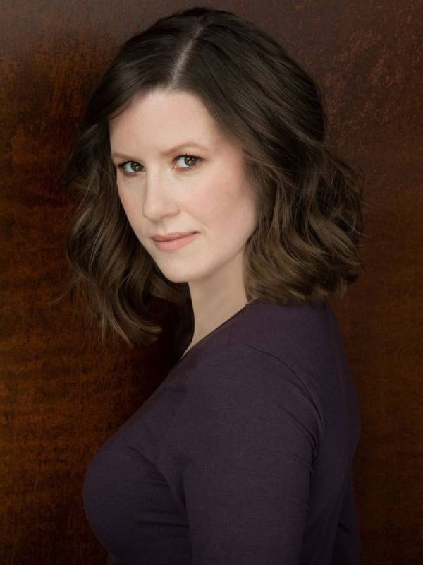 Victoria Sullivan’s headshot. She has shoulder-length brown hair and wears a purple shirt. 