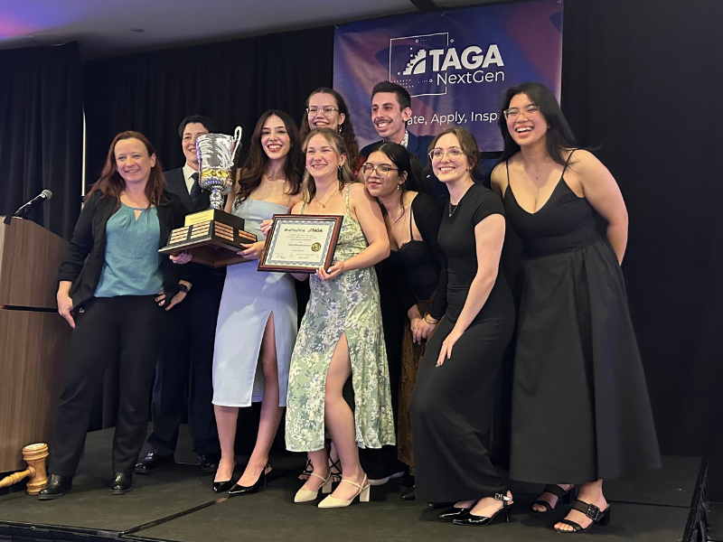 A group of people smiling, holding up a trophy and certificate.