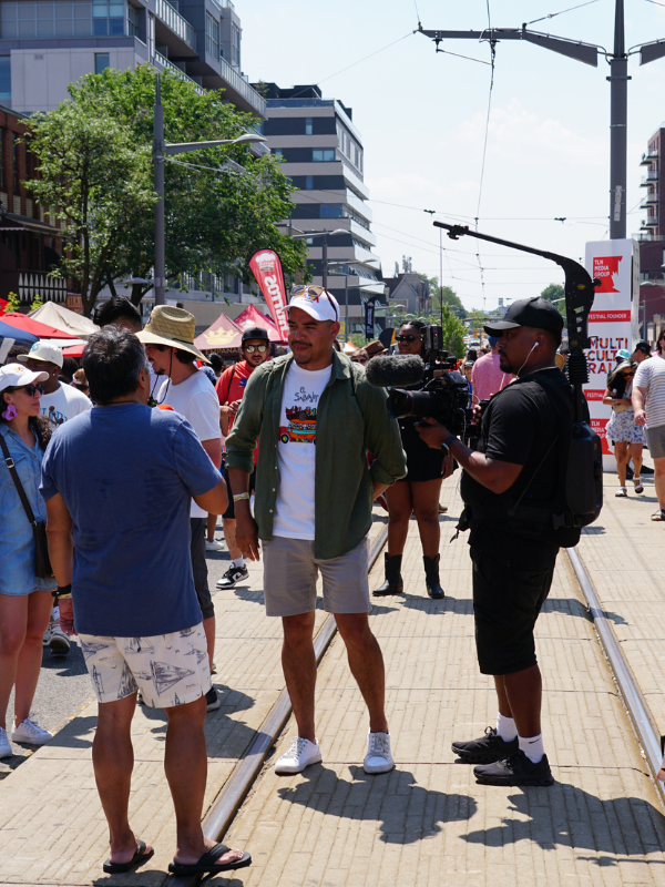 Photo shows José Rosales and a cameraman interviewing someone at the outdoor festival.
