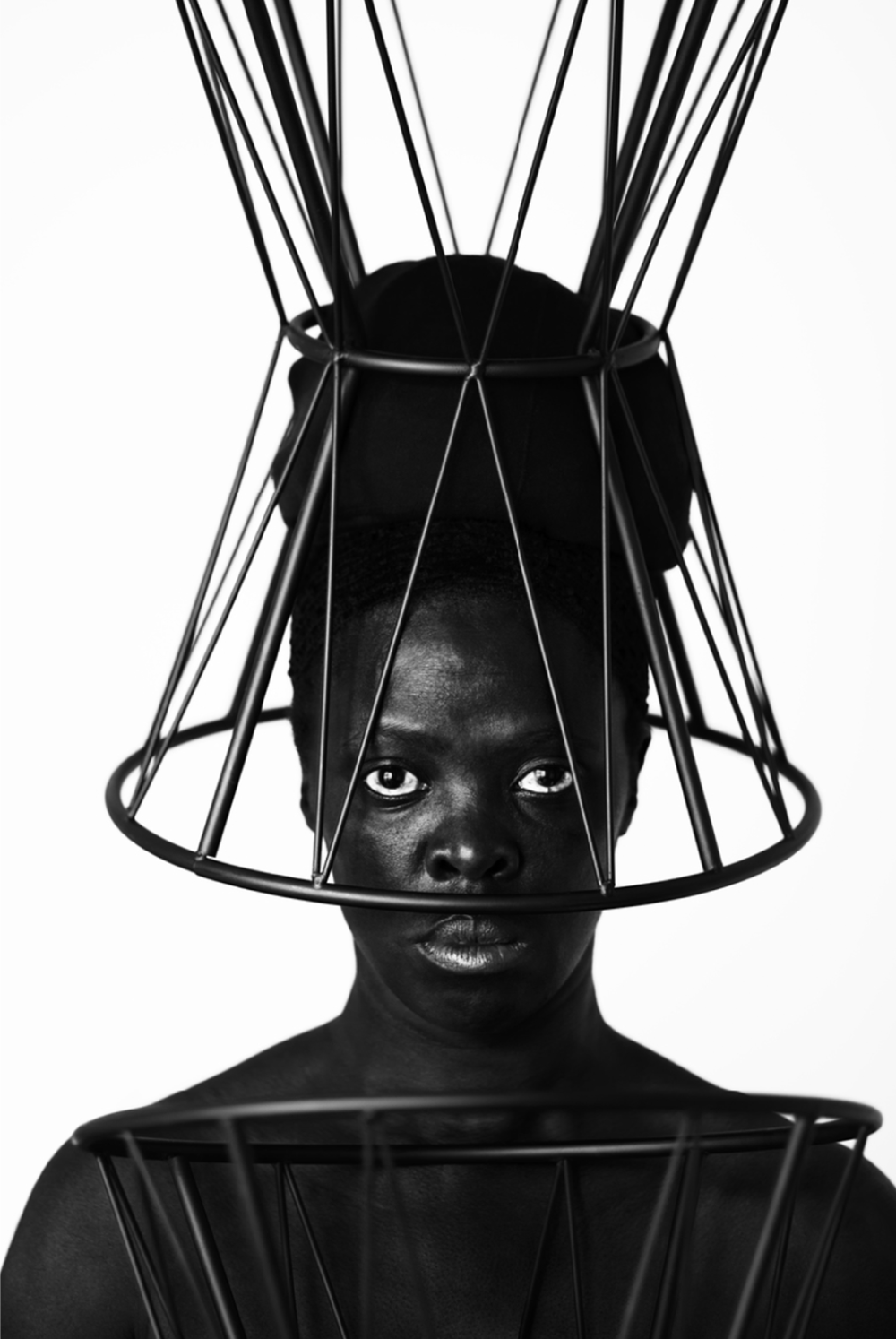 Person with a large metal headpiece staring directly into camera