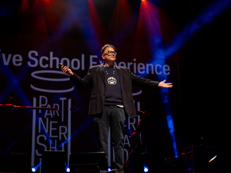 Man standing on a stage with his hands out wide