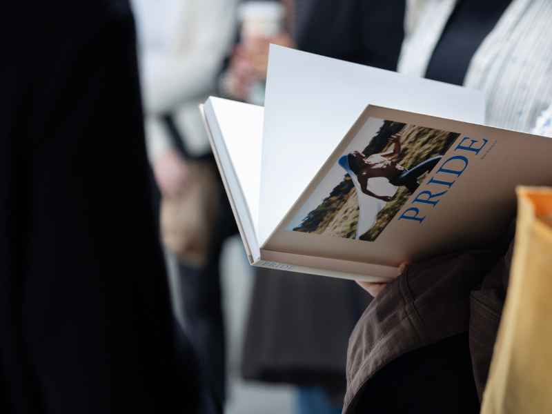 A close-up of a person holding an open book or magazine titled "PRIDE."