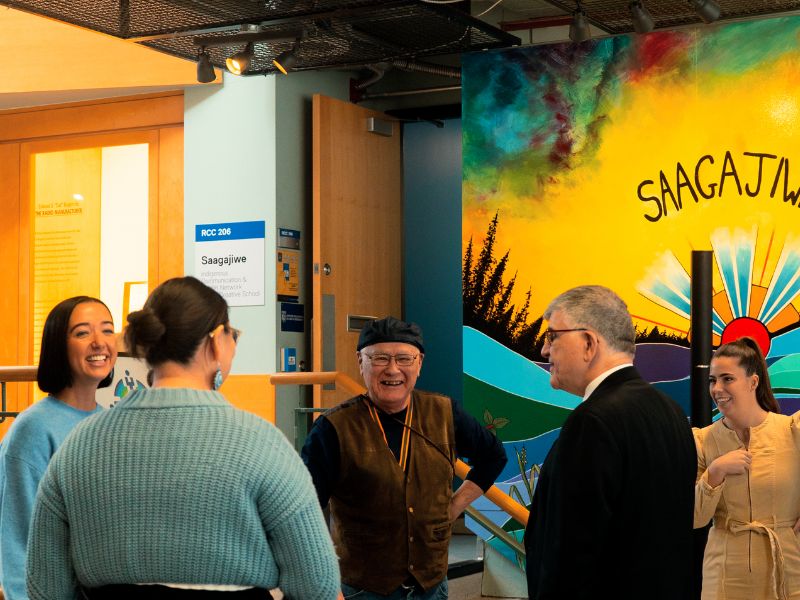 A group of people stand in a circle laughing mid-conversation.