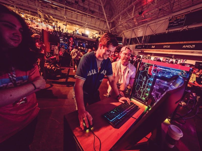 Person typing on a keyboard and looking at a computer screen with people surrounding his table. 