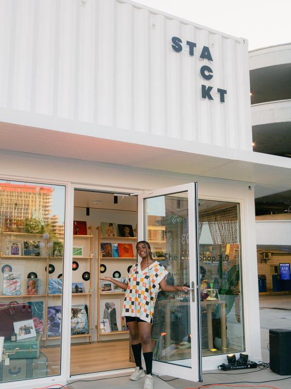 Busby stands in front of a shop with the door open. 