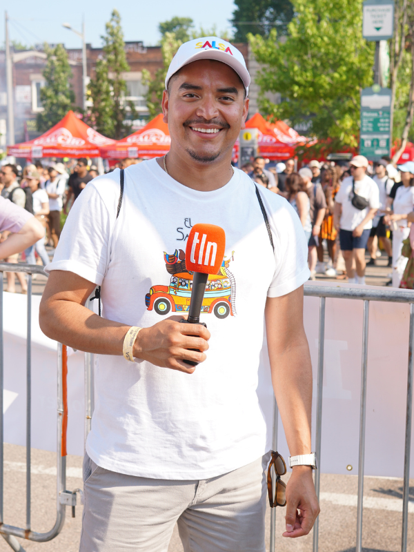 photo shows an outdoor medium-long shot of José Rosales smiling and posing with a TLN microphone in his hand.