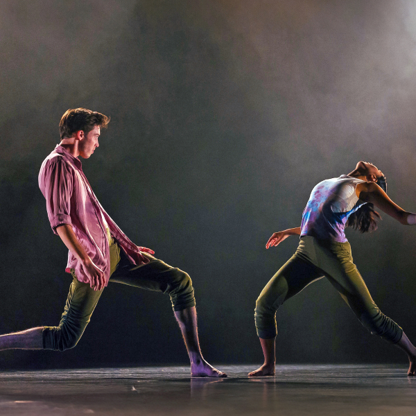 Dramatic wide shot of two dancers making elaborate full body moves on an empty stage