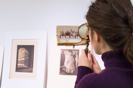 Person using magnifying glass to look at a archival image