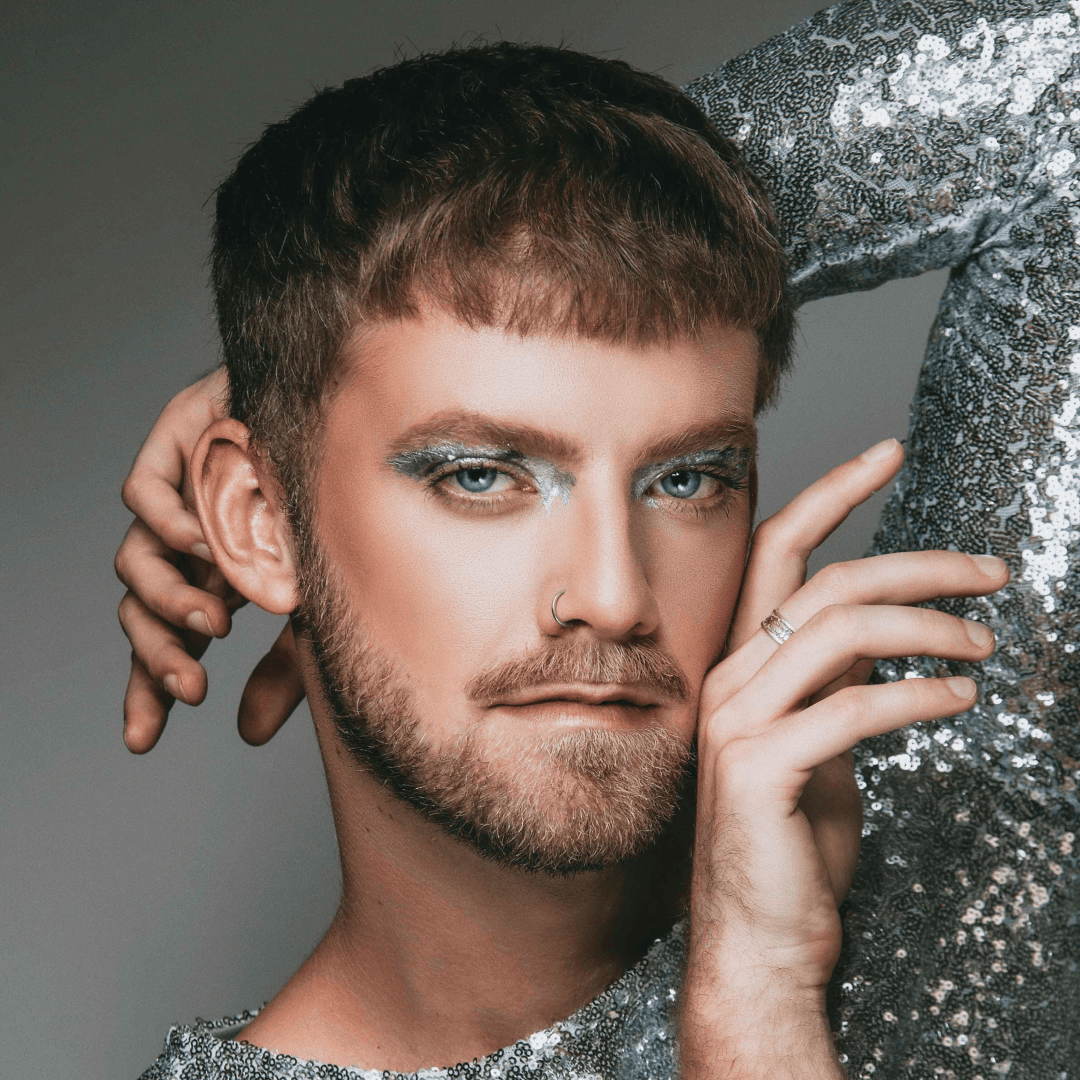 Headshot of Darren Creech posing with arm behind head and wearing a silver shirt
