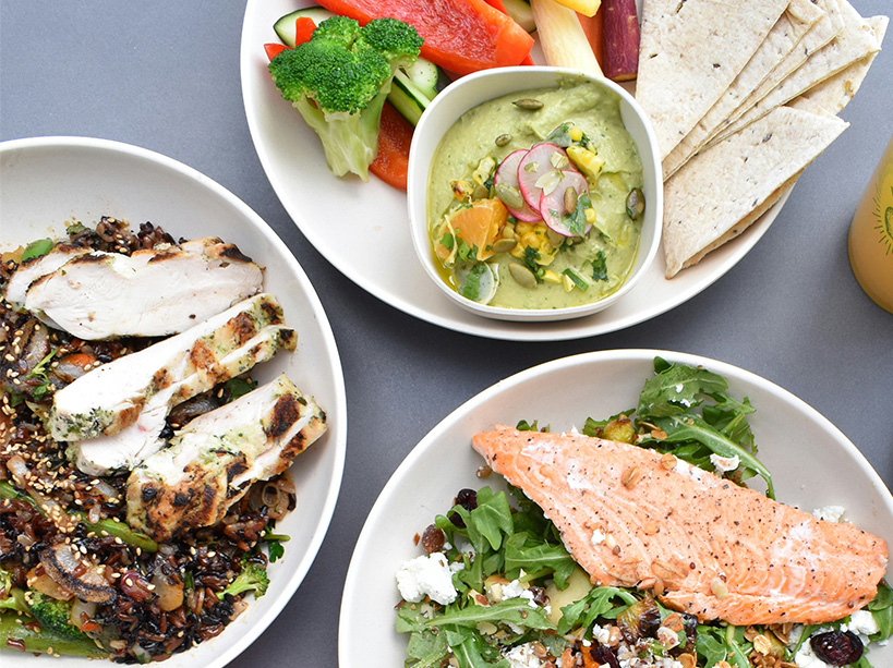An overhead view of three white bowls filled with colourful, healthy meal options.