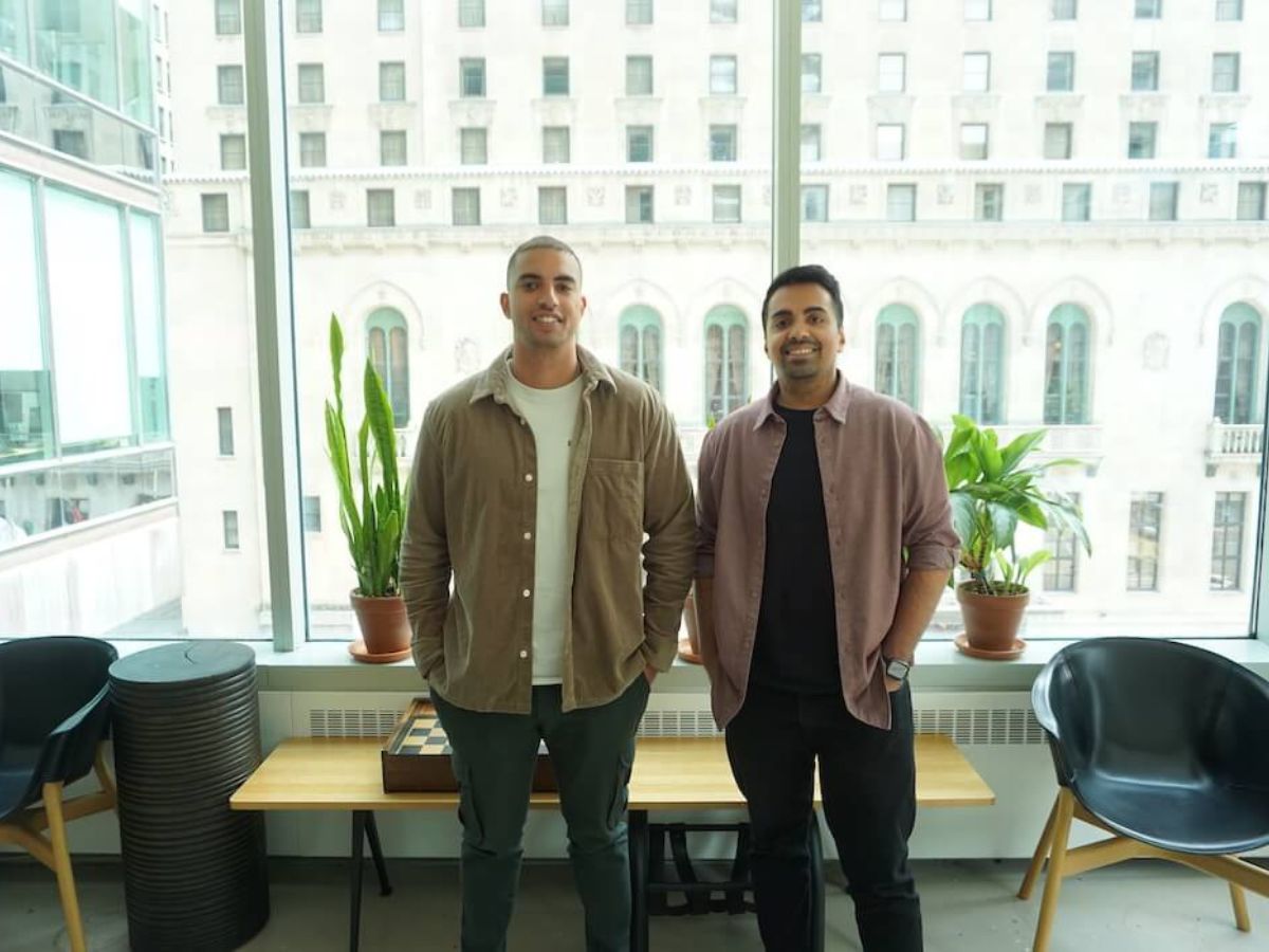 Two men in an office standing with hands in pockets in front of a window