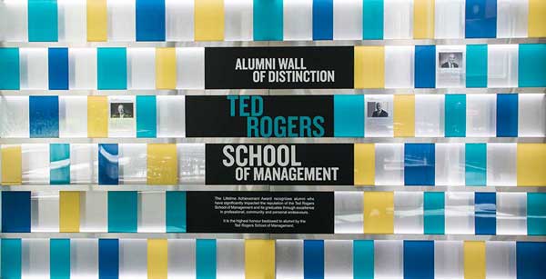 Wall of blue, teal and yellow tiles with the words Alumni Wall of Distinction and Ted Rogers School of Management in the title