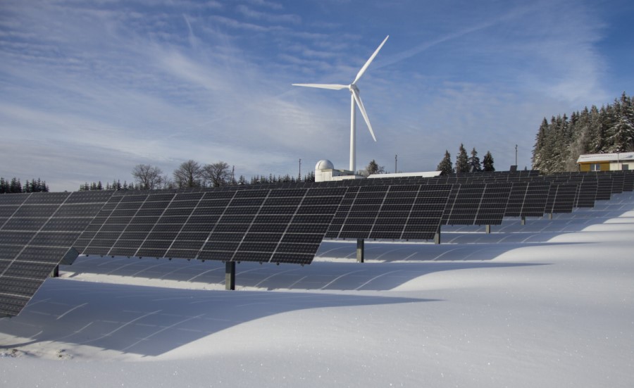 solar panels and a windmill standing  on the snow