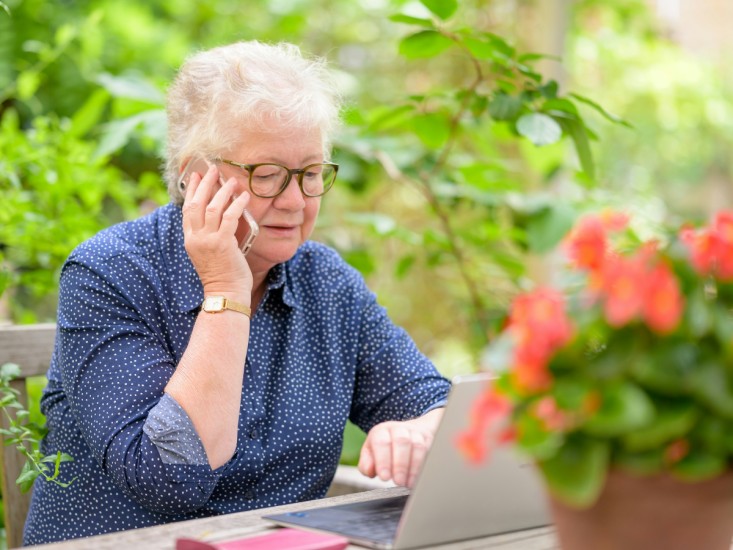 person on phone with laptop in front