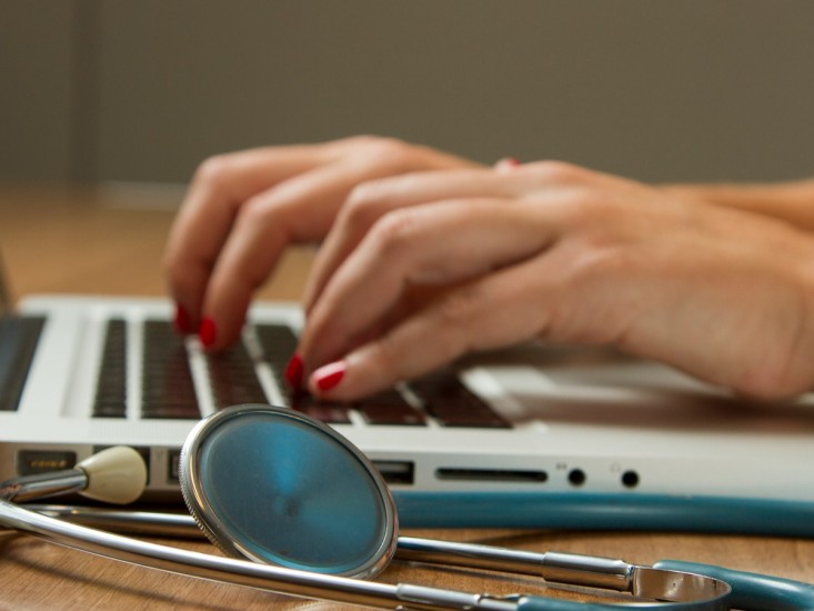 stethescope next to a person's hands on a laptop