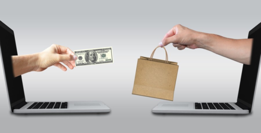 hand stretching from two laptops facing each other with a bag in one hand and currency note in another hand