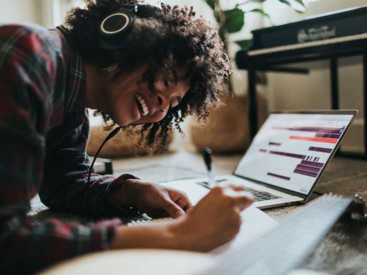person with a headset, smiling and writing