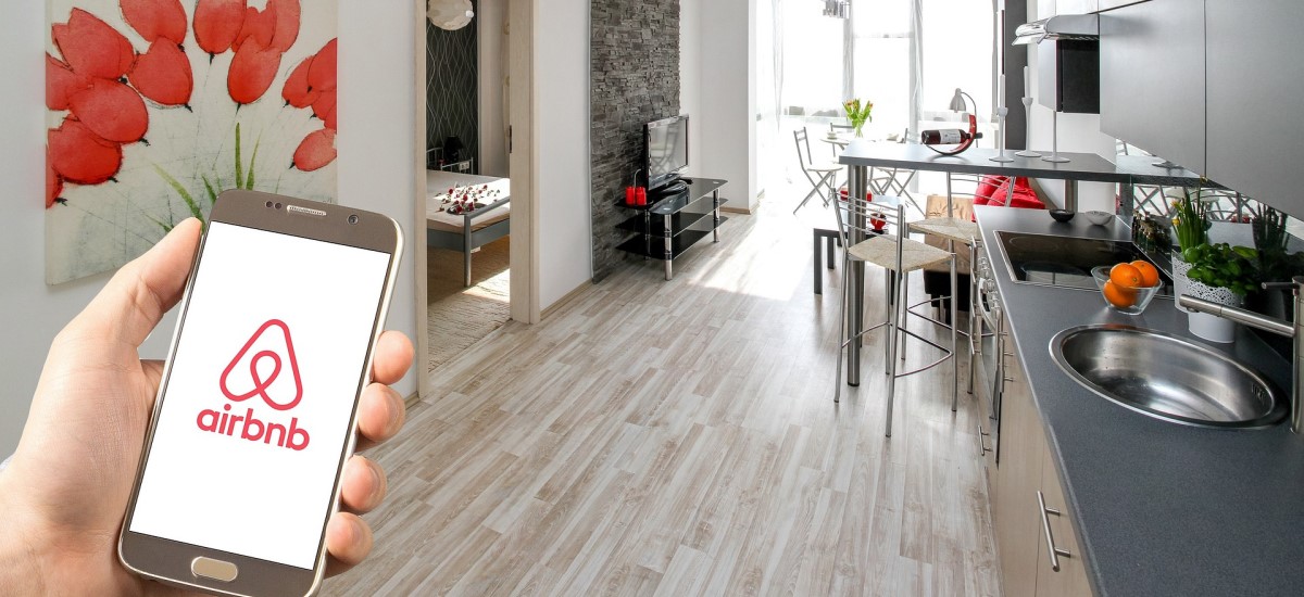 airbnb logo on a smartphone held around a living space
