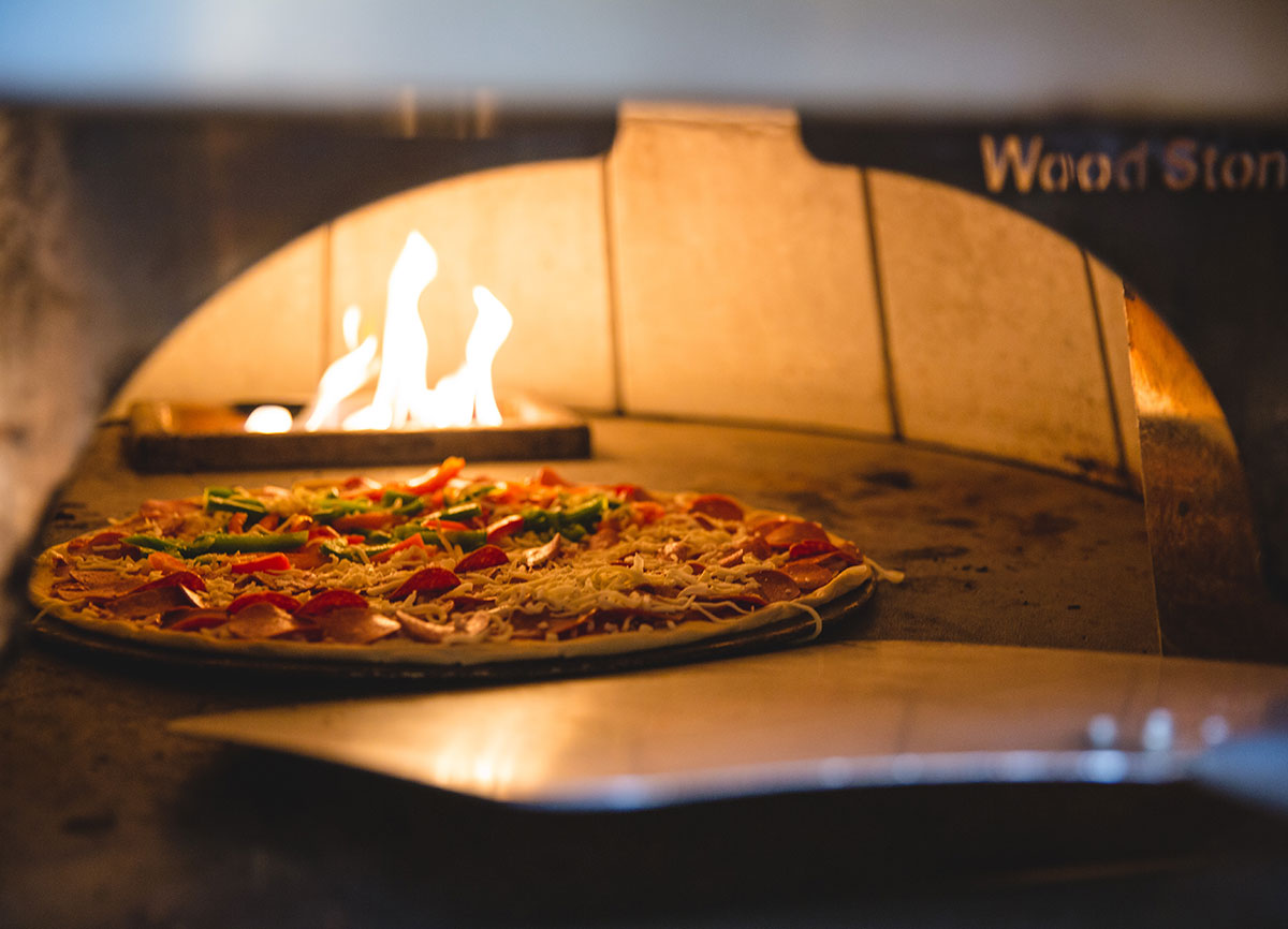 A pizza baking in a hot oven, flames in the background.