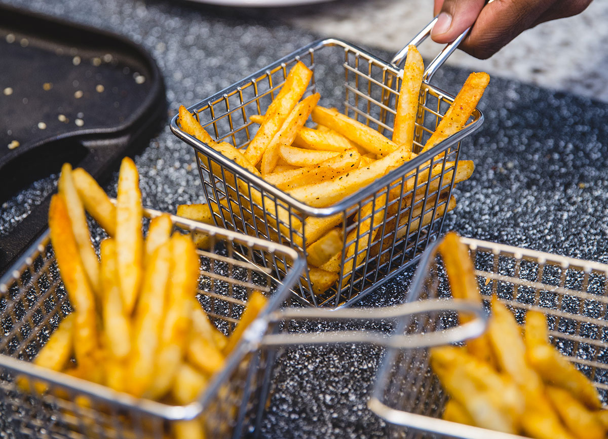 Hot, fresh cut fries in a wire basket.