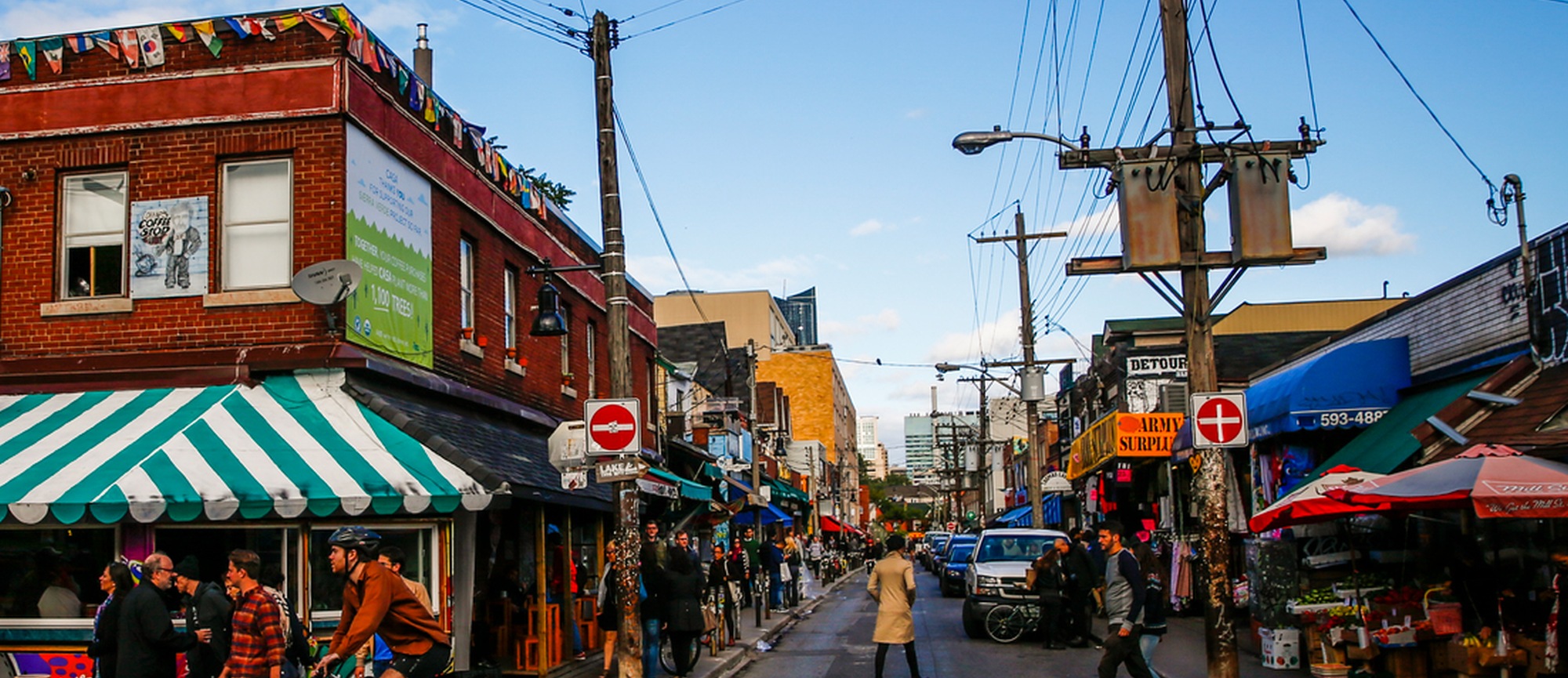 A bustling street in Toronto's Kensington market with shop awnings 