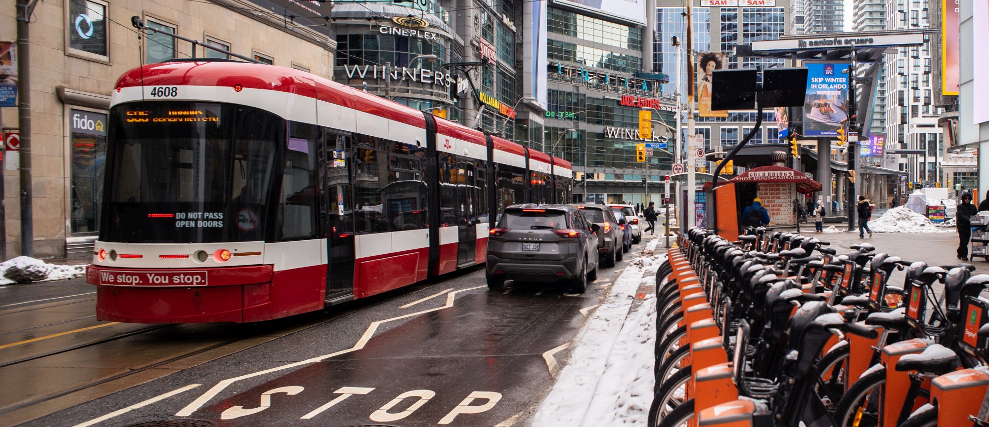 Facing Sankofa Square, a shot of the road with a streetcar and a row of orange bike share bikes in focus