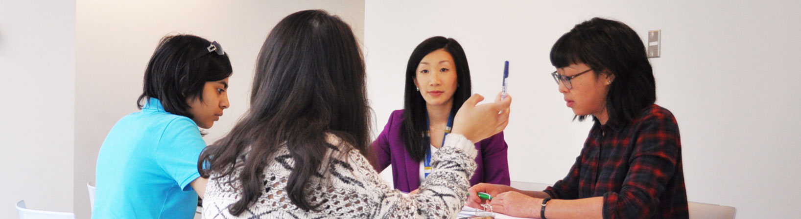 Four women working at a table collaborating on a project.