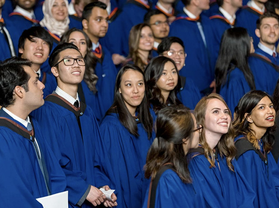 Excited graduates wearing blue Bachelor’s gowns, waiting to receive their diploma at convocation.