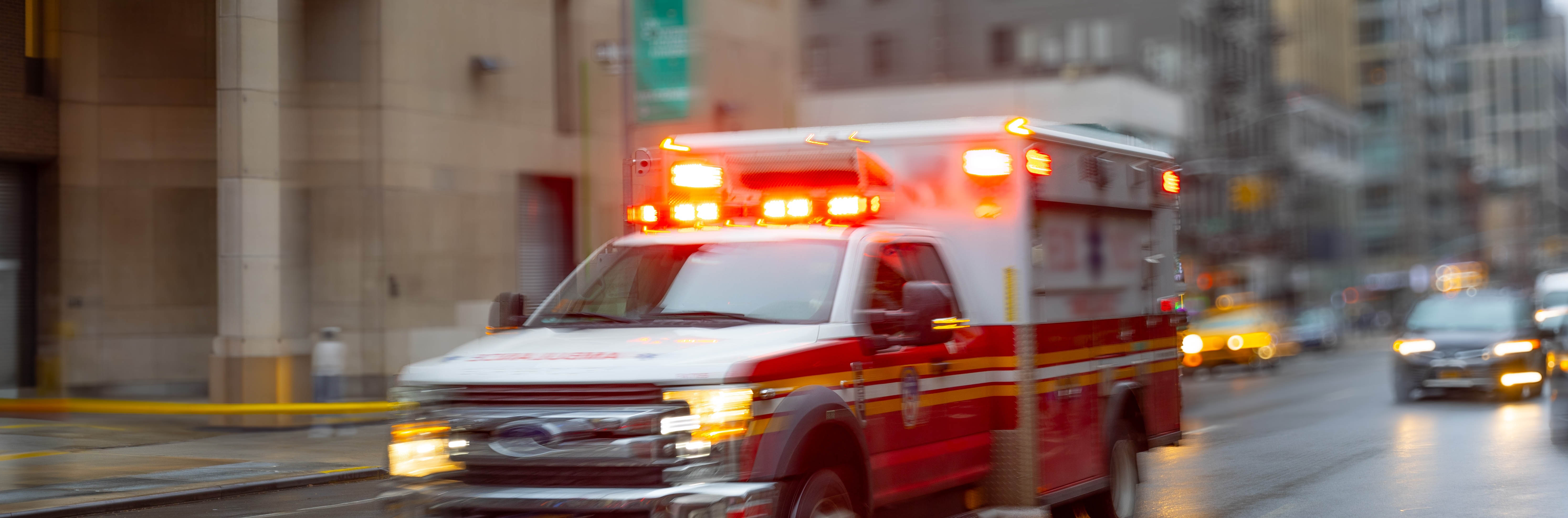 Ambulance with emergency lights activated speeding down a street.