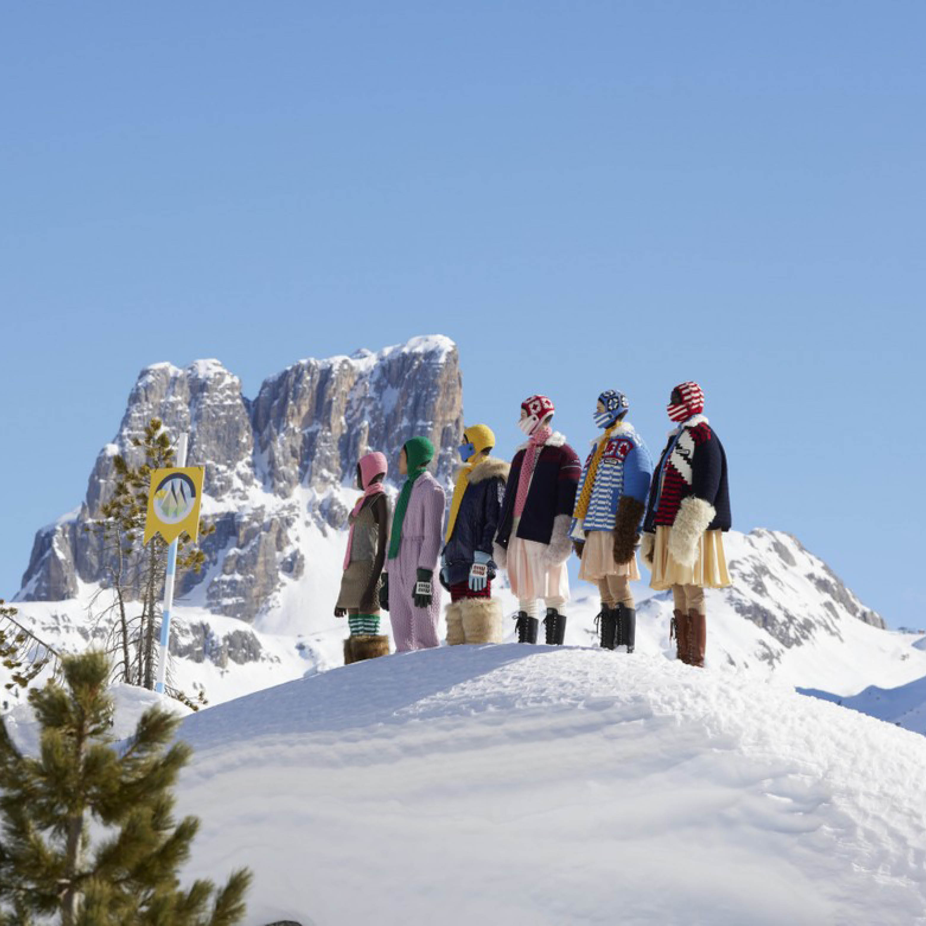 Miu Miu models in thick jackets atop of a snowy mountain.