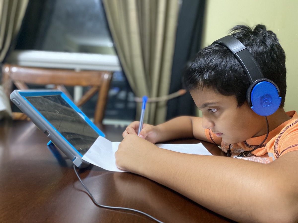 Child wearing Wave headphones while working on a tablet