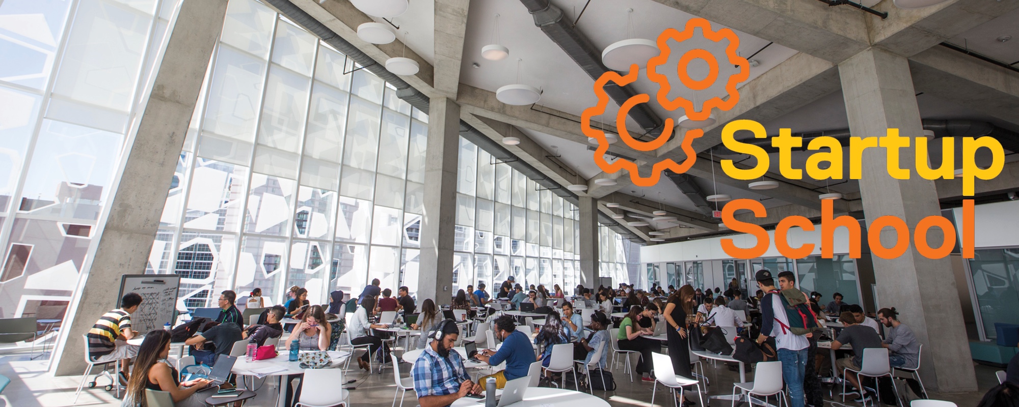 Startup School logo over an image of students working in an open space