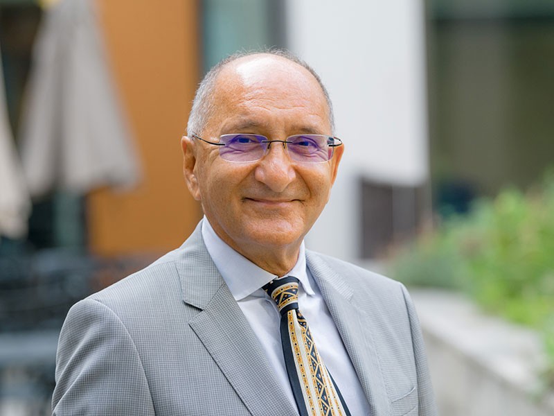 Anver Saloojee smiles in a grey suit with tie