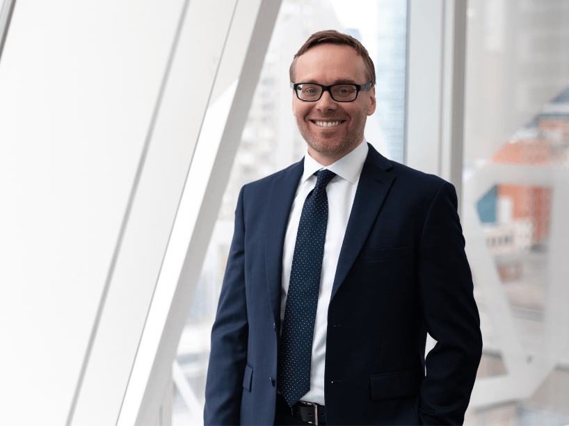 Cory Searcy smiles and stands in a black suit