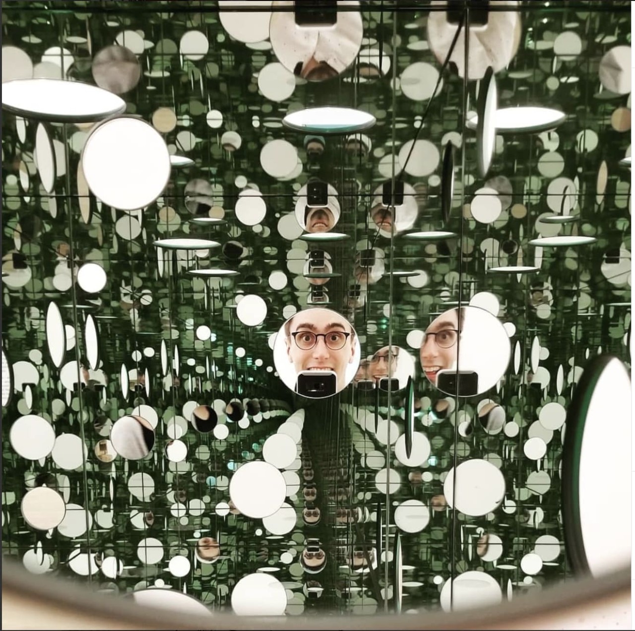 Sam's face in a small circular mirror with many reflections around it.