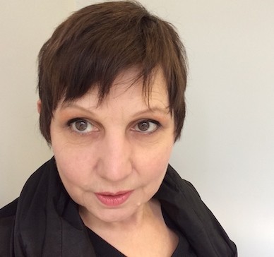 Kathleen looks to the left. She has short hair and brown eyes.