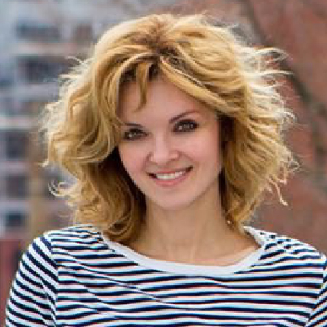 Close-up headshot of Ramona Pringle smiling. He has curly blonde hair and is wearing a black-and-white striped shirt.