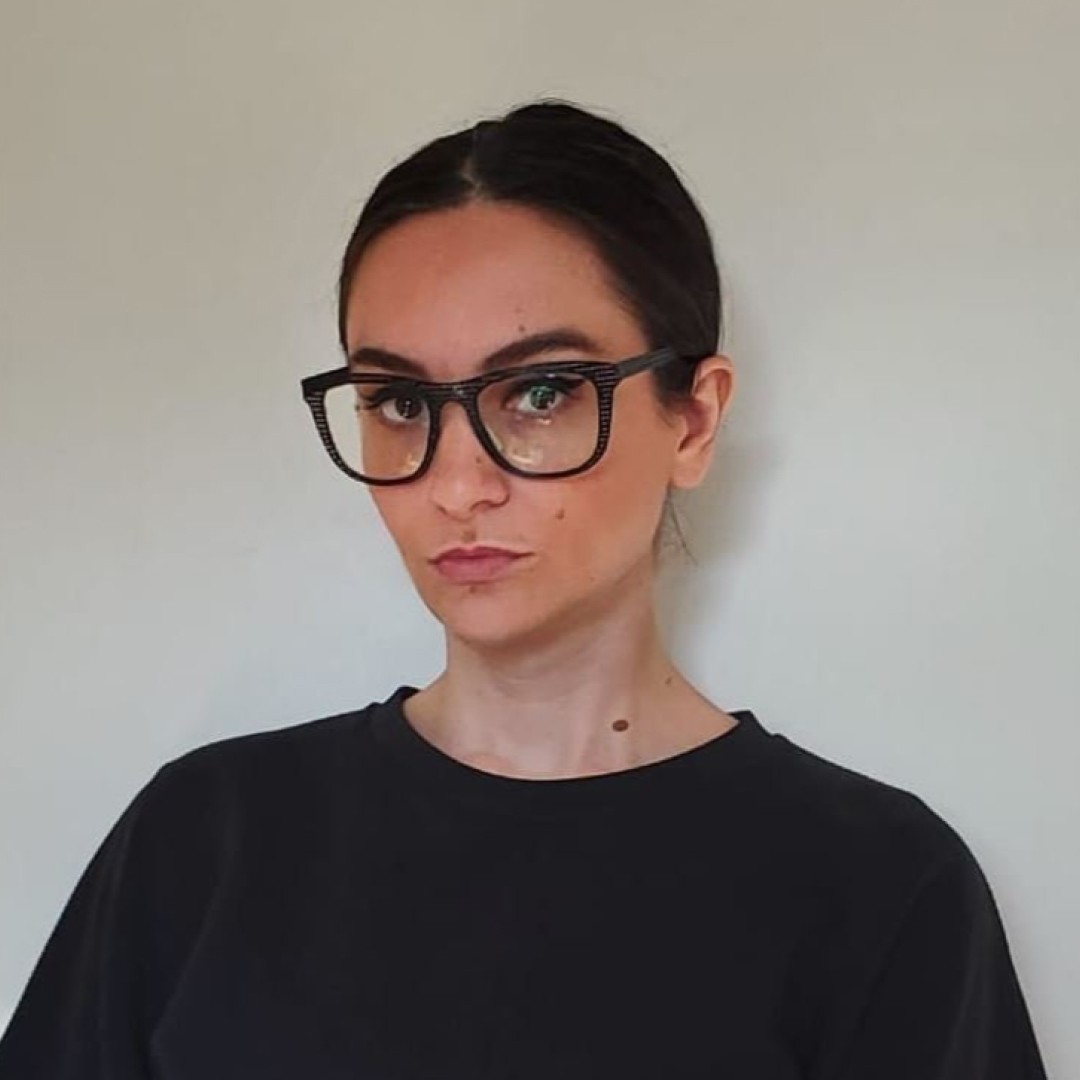 Headshot of Viola Ago wearing black blouse and glasses