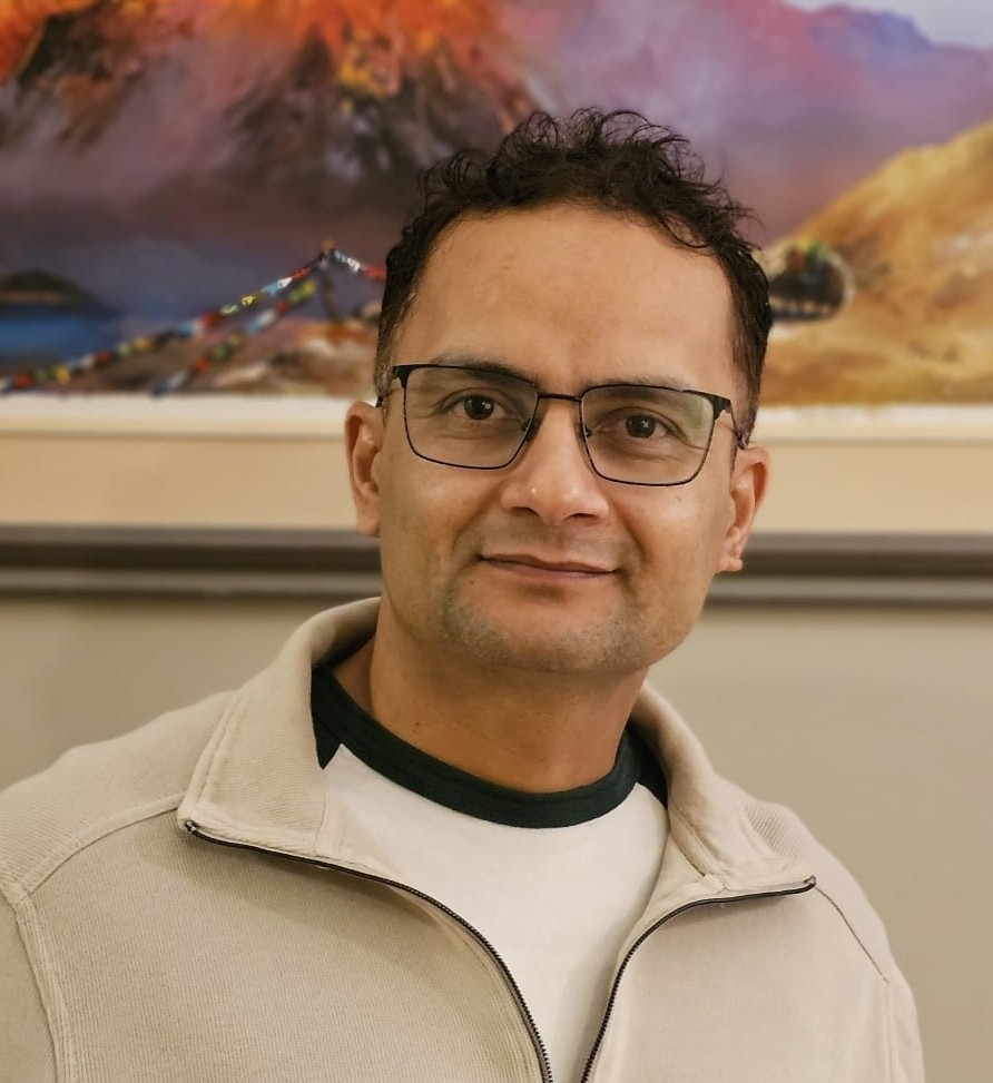 Anil Dhakal wearing a beige quarter zip infront of a painting