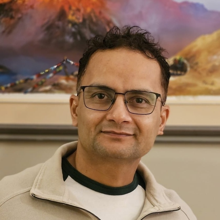 Anil Dhakal wearing a beige quarter zip infront of a painting